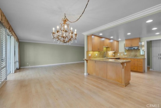 32709 Seagate Dr Unit 101, Rancho Palos Verdes, CA 90275 - kitchen with baseboards, crown molding, under cabinet range hood, backsplash, and light wood-style floors