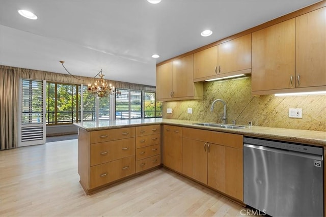 kitchen with a peninsula, a sink, stainless steel dishwasher, light stone countertops, and light wood finished floors