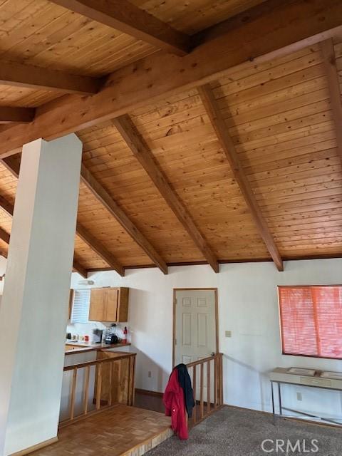 interior space featuring lofted ceiling with beams, carpet flooring, and wooden ceiling