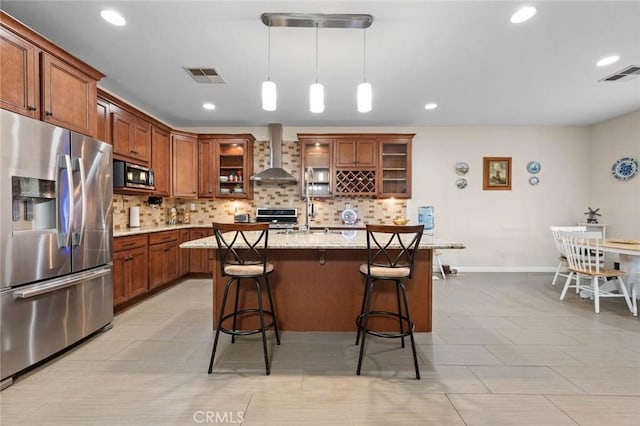 kitchen featuring visible vents, appliances with stainless steel finishes, wall chimney range hood, and glass insert cabinets