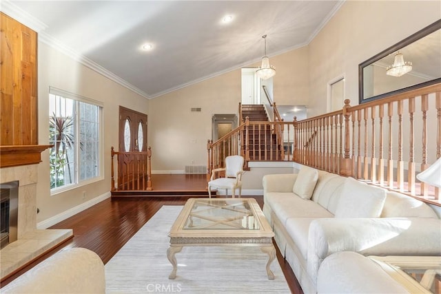 living room featuring dark hardwood / wood-style floors, high vaulted ceiling, a tiled fireplace, and ornamental molding