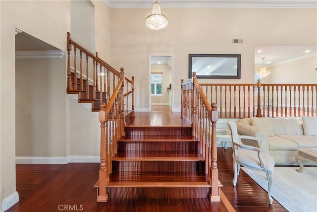 staircase with hardwood / wood-style flooring, a chandelier, and crown molding