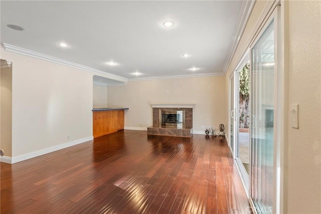 unfurnished living room with ornamental molding, a tiled fireplace, and dark hardwood / wood-style floors