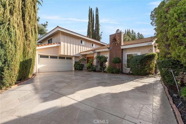 1885 Fallview Rd, Westlake Village, CA 91361 - view of front facade with a chimney, concrete driveway, stucco siding, an attached garage, and a tiled roof