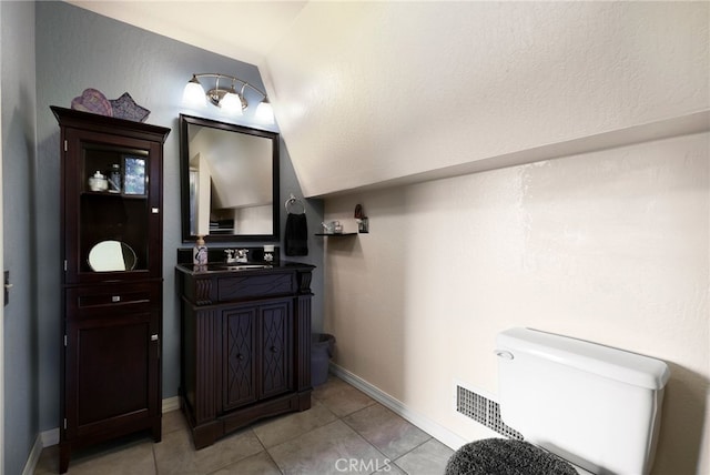 bathroom featuring vanity, tile patterned flooring, vaulted ceiling, and toilet