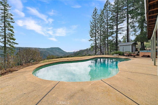 view of swimming pool with a hot tub, a mountain view, a patio, and a diving board