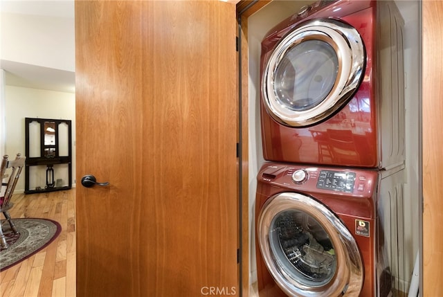 washroom with wood-type flooring and stacked washer and clothes dryer