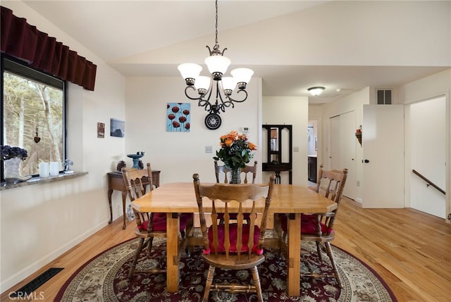 dining area with lofted ceiling, light hardwood / wood-style flooring, and an inviting chandelier