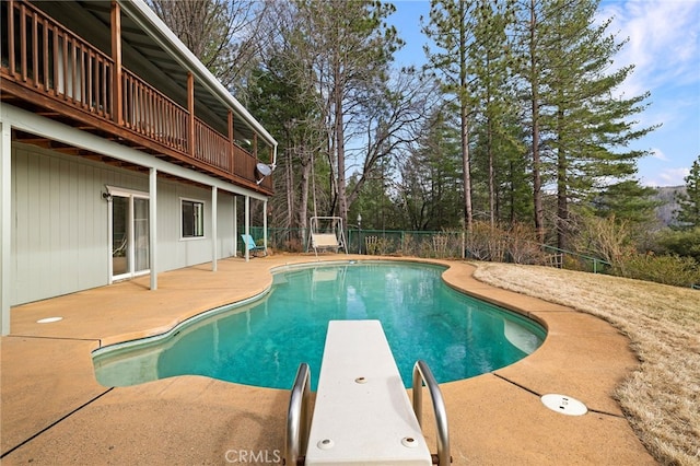 view of swimming pool featuring a patio and a diving board