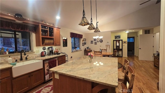 kitchen featuring lofted ceiling, sink, a breakfast bar area, hanging light fixtures, and a kitchen island