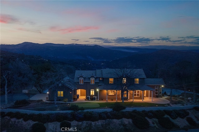 back of property at dusk with a patio area and a mountain view