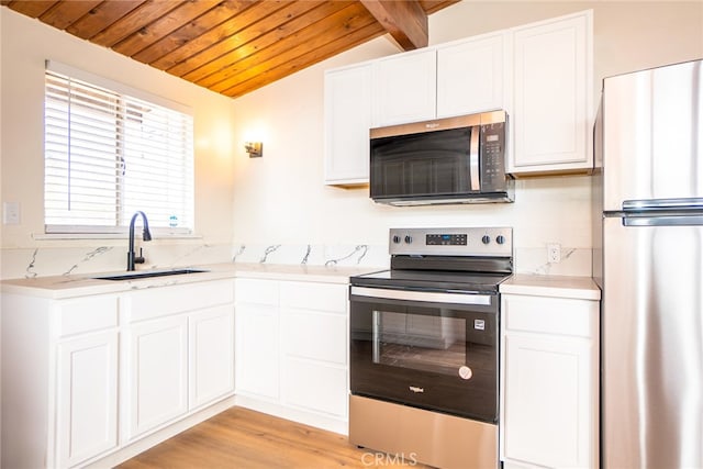 kitchen featuring white cabinetry, vaulted ceiling with beams, and stainless steel appliances