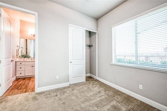 unfurnished bedroom featuring light colored carpet, a closet, and ensuite bathroom