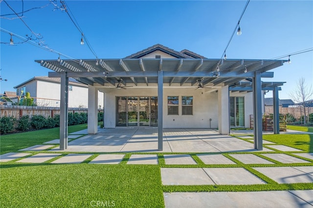 back of property with ceiling fan, a yard, a pergola, and a patio area