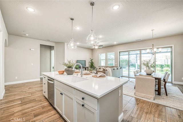 kitchen featuring sink, white cabinetry, hanging light fixtures, a center island with sink, and stainless steel dishwasher