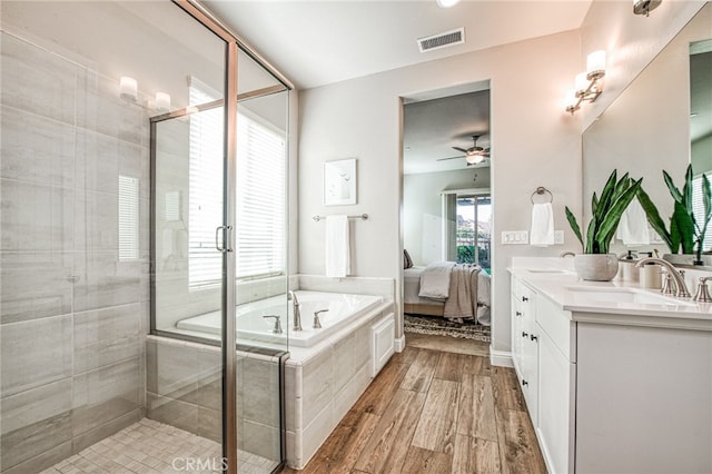 bathroom with hardwood / wood-style flooring, ceiling fan, vanity, and shower with separate bathtub