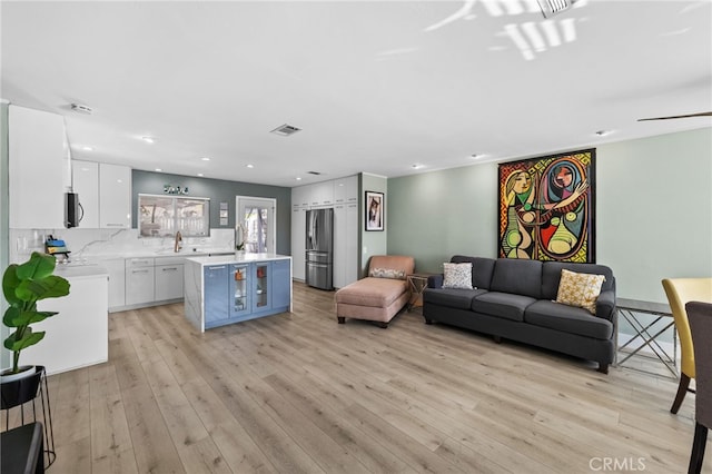 living room featuring sink and light hardwood / wood-style flooring