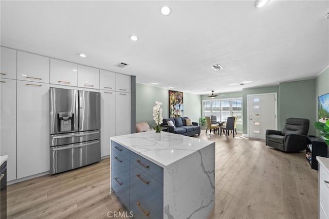 kitchen featuring a kitchen island, white cabinets, light hardwood / wood-style floors, stainless steel refrigerator with ice dispenser, and light stone countertops