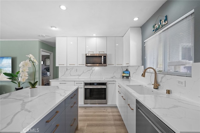 kitchen featuring light stone counters, sink, white cabinets, and appliances with stainless steel finishes