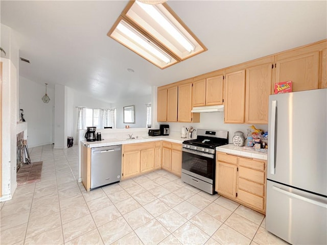 kitchen with light brown cabinetry, tile countertops, stainless steel appliances, lofted ceiling, and sink