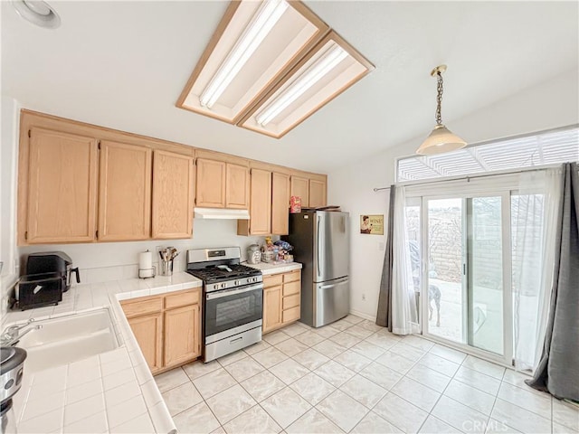 kitchen featuring appliances with stainless steel finishes, sink, pendant lighting, light brown cabinets, and tile countertops