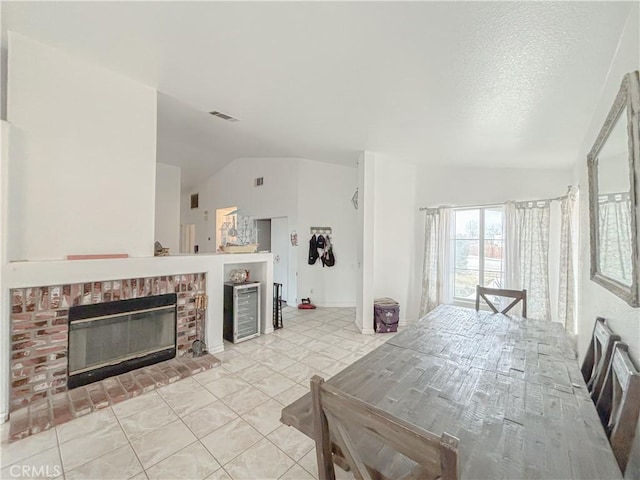 dining area with a textured ceiling, vaulted ceiling, a fireplace, light tile patterned floors, and heating unit