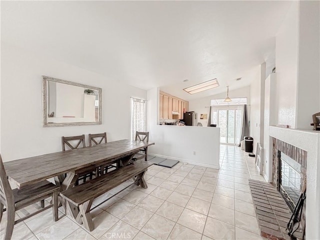 tiled dining space with lofted ceiling and a brick fireplace