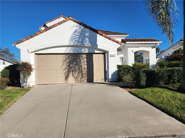 mediterranean / spanish-style home with a garage, a tiled roof, concrete driveway, and stucco siding