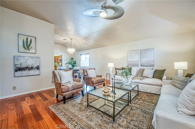 living room with lofted ceiling, dark wood-type flooring, and ceiling fan with notable chandelier