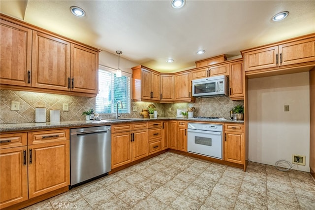1585 W Riverglen Ave, Reedley, CA 93654 - kitchen with decorative light fixtures, sink, dark stone countertops, backsplash, and stainless steel appliances