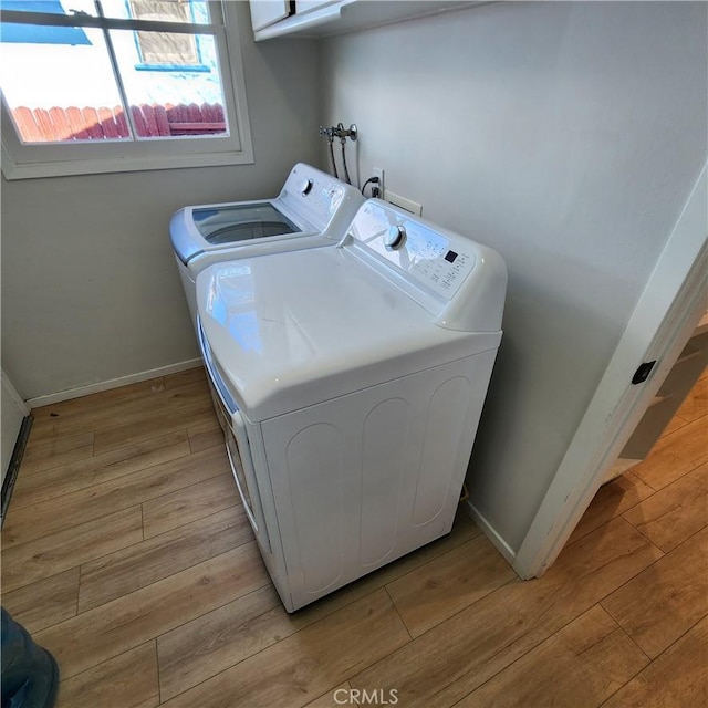 laundry room with washing machine and dryer and light hardwood / wood-style floors