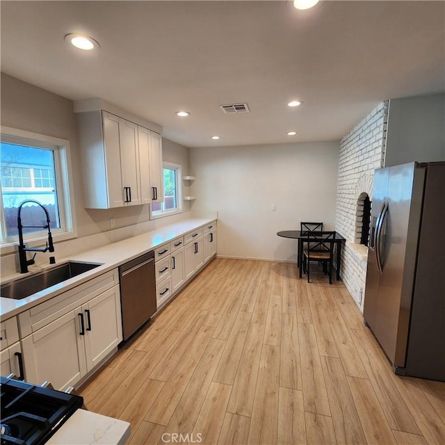 kitchen with sink, stainless steel appliances, light hardwood / wood-style floors, and white cabinets