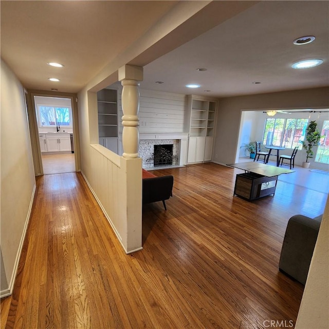 corridor with sink, light wood-type flooring, and built in shelves