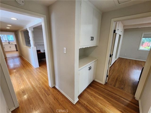 hallway featuring sink, light hardwood / wood-style floors, and a wealth of natural light