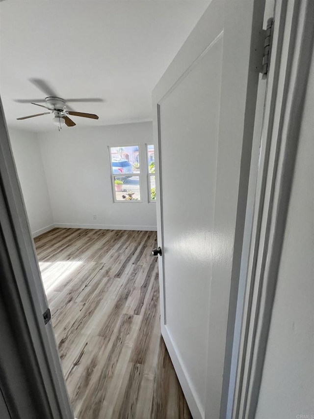 empty room with ceiling fan and light wood-type flooring