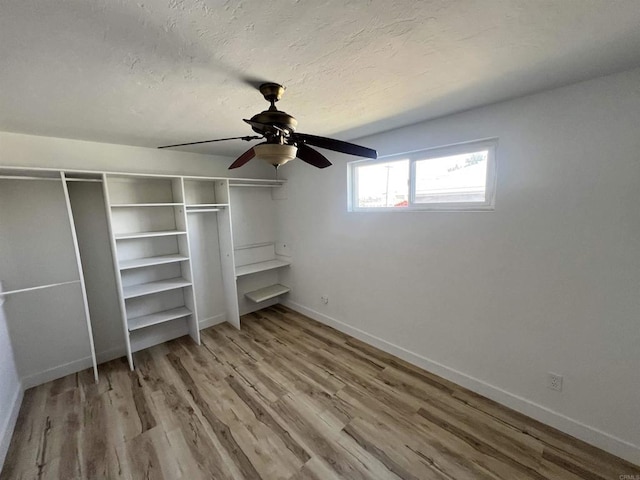 unfurnished bedroom with ceiling fan, a textured ceiling, light wood-type flooring, and a closet