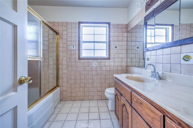 full bathroom featuring tile walls, vanity, bath / shower combo with glass door, and toilet