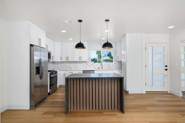 kitchen with a kitchen island, decorative light fixtures, sink, white cabinets, and stainless steel appliances