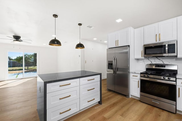 kitchen featuring a kitchen island, appliances with stainless steel finishes, white cabinets, and decorative light fixtures