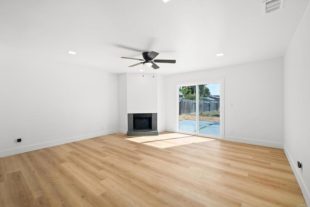 unfurnished living room featuring ceiling fan, a multi sided fireplace, and light wood-type flooring