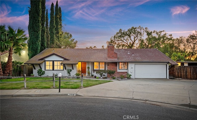 ranch-style house featuring a garage, concrete driveway, a chimney, a tiled roof, and a front lawn