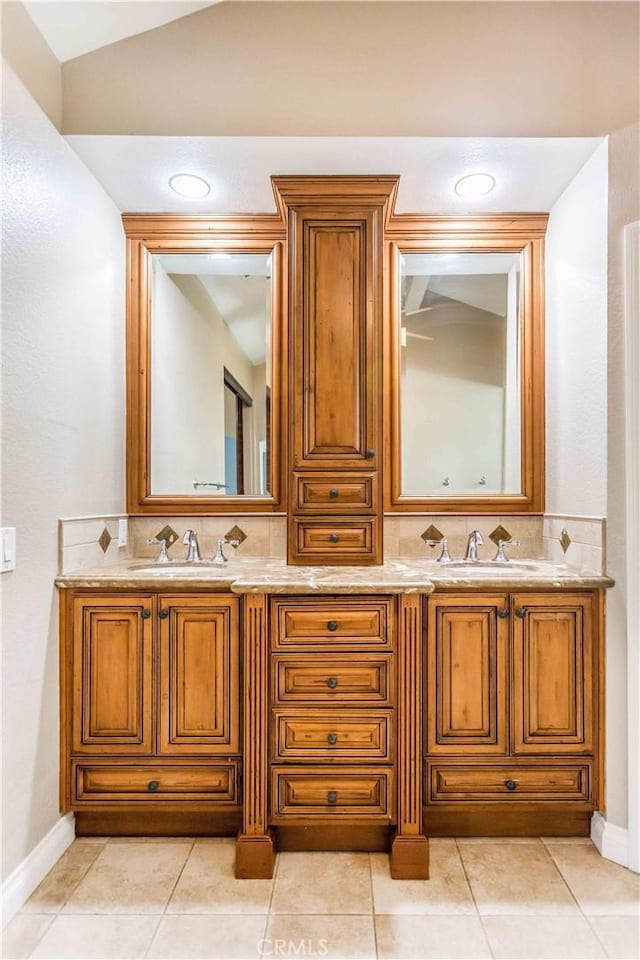 bathroom with double vanity, a sink, backsplash, and tile patterned floors