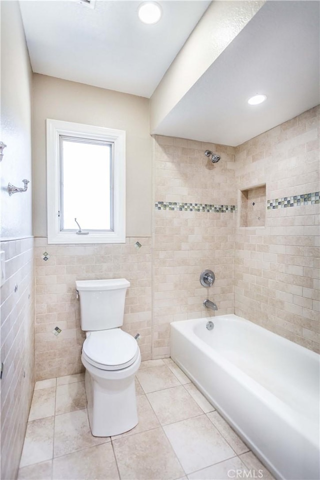 full bathroom with tile patterned flooring, toilet, a wainscoted wall, tile walls, and shower / washtub combination