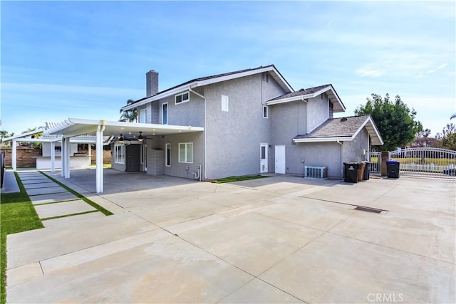 back of property with a chimney, a gate, a pergola, and concrete driveway