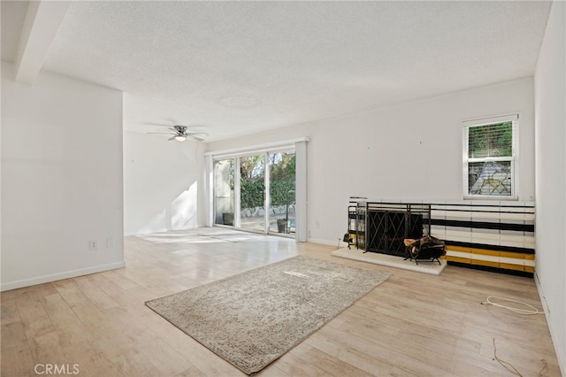 living room featuring a textured ceiling, ceiling fan, and light hardwood / wood-style flooring