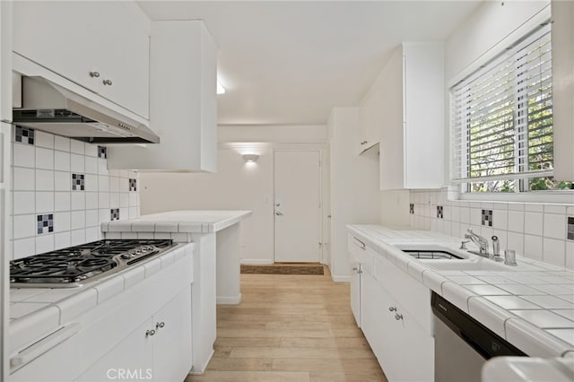 kitchen with white cabinets, stainless steel appliances, extractor fan, and tile countertops