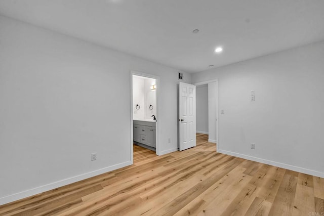 unfurnished bedroom with light hardwood / wood-style flooring, sink, and ensuite bathroom