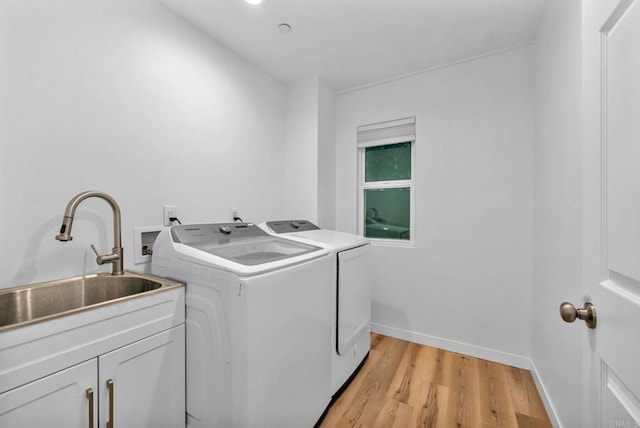 washroom featuring cabinets, washing machine and dryer, sink, and light hardwood / wood-style flooring