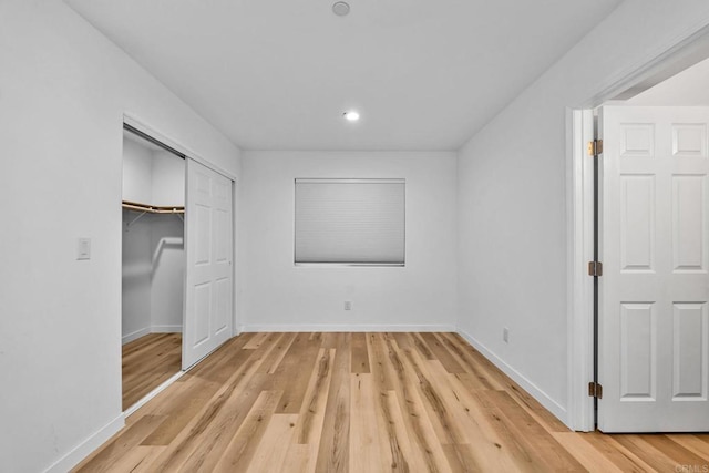 unfurnished bedroom with a closet and light hardwood / wood-style floors