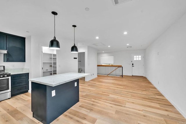 kitchen with light stone counters, decorative light fixtures, a center island, stainless steel range with gas cooktop, and light wood-type flooring